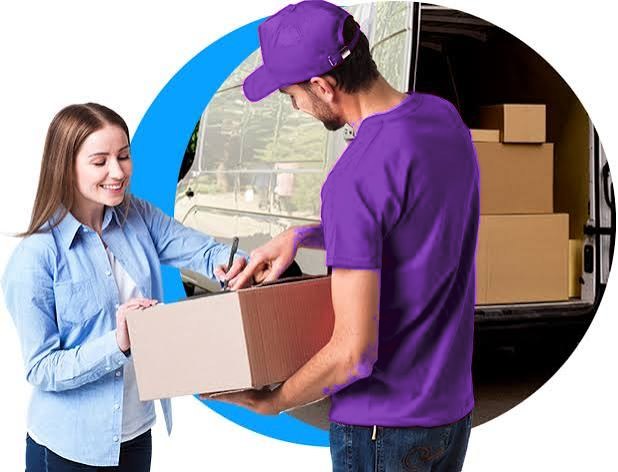 Courier in a purple uniform handing a parcel to a customer
