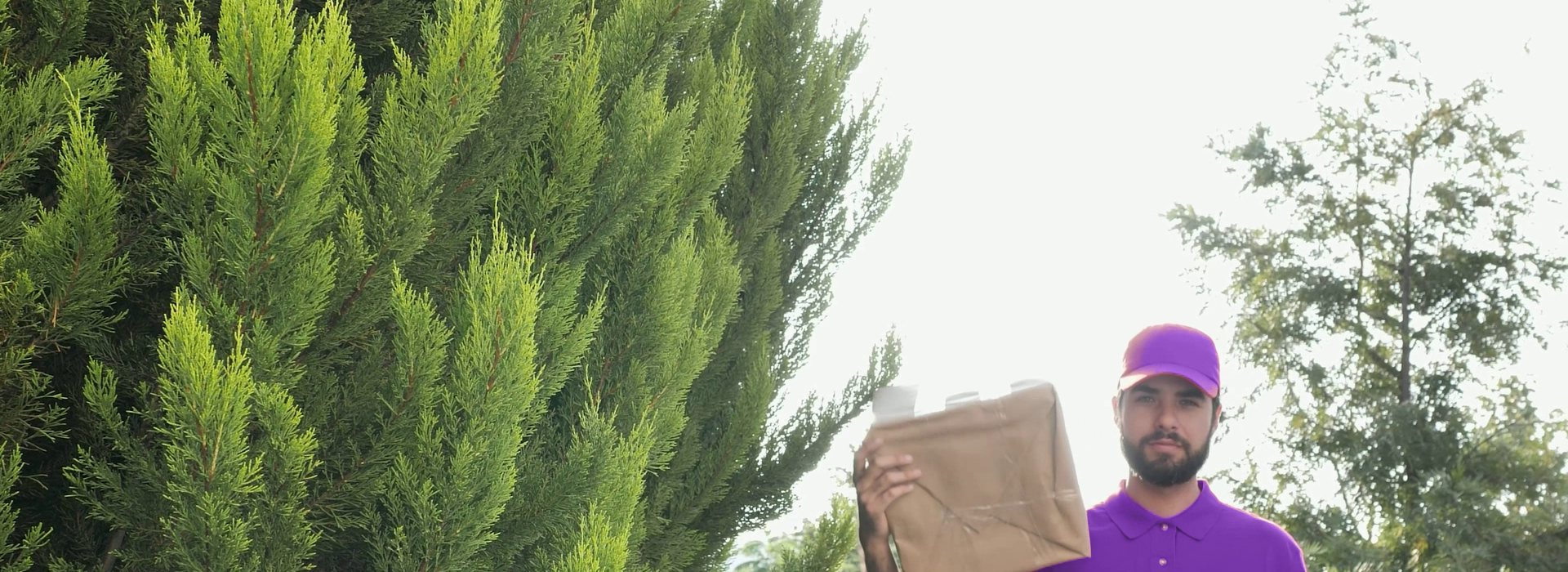 Courier in a purple uniform carrying a parcel