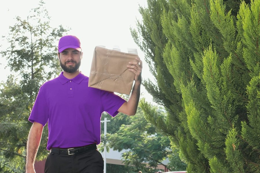 Courier in a clean purple uniform carrying a parcel